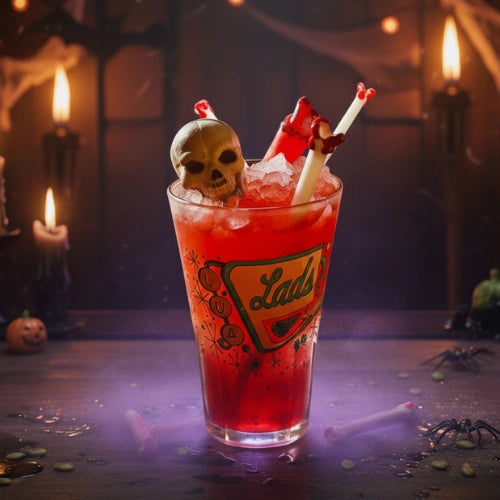 Surfside Sips glass "Bloody Bone" straw in a spooky red cocktail with ice, skull garnish, and candy bone decorations, perfect for Halloween drinks.