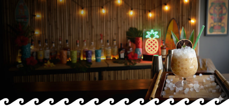 Glass Tiki Bamboo Straws from Surfside Sips are perfect for tropical cocktails like this tiki drink, complete with a pineapple garnish and crushed ice, served on a bamboo tray at a warm, inviting tiki bar.