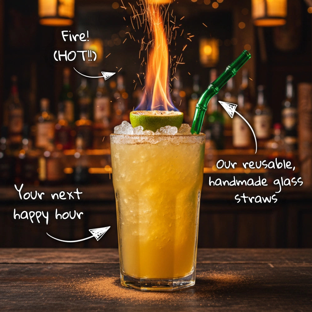 A vibrant tiki cocktail topped with a flaming lime garnish and served with a green reusable glass straw. Playful handwritten notes with arrows point to the drink, flame, and straw, reading ‘Fire! (HOT!!)’, ‘Your next happy hour’, and ‘Our reusable, handmade glass straws’. The scene is set in a cozy tiki bar with warm lighting and bottles in the background.